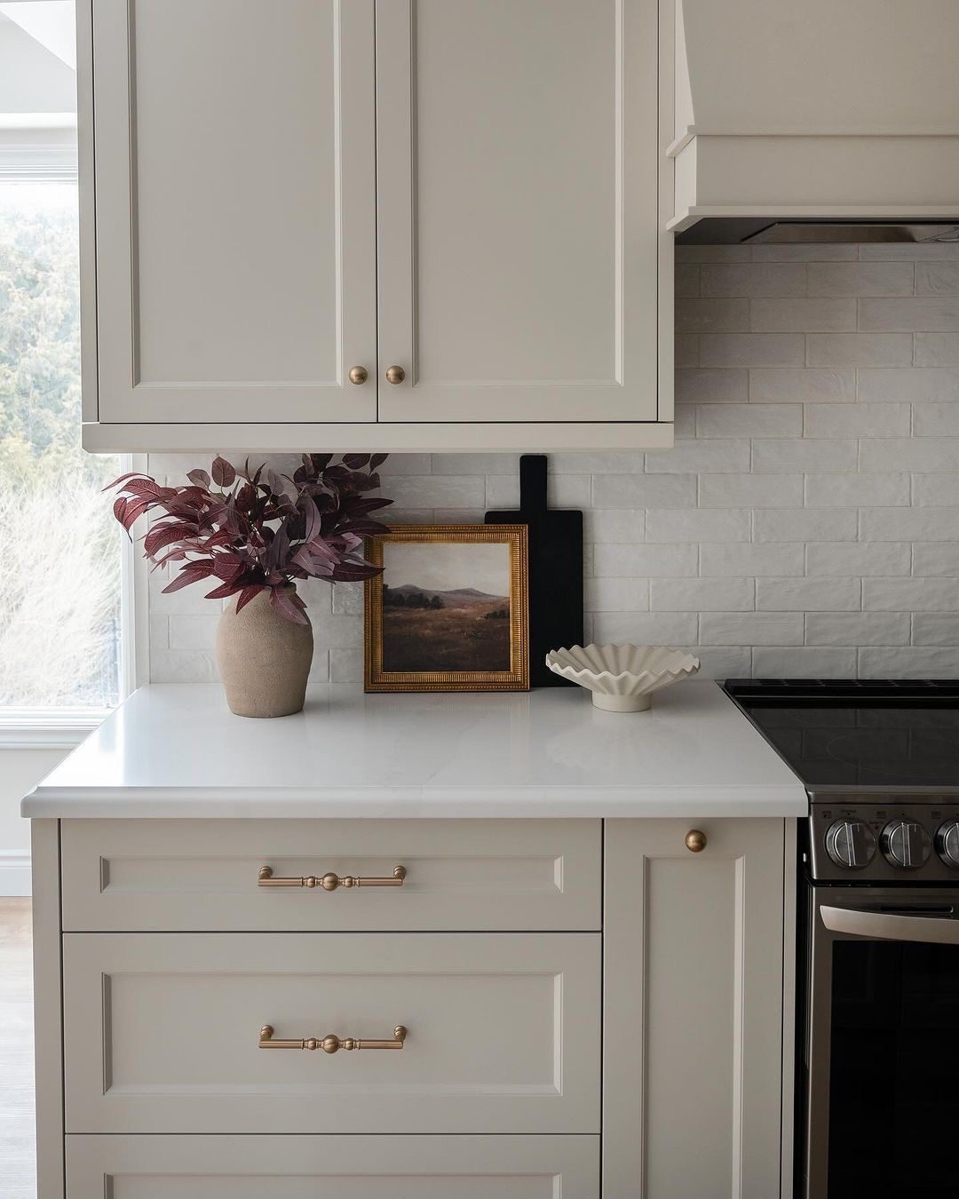 کابینت نئوکلاسیک سفید با دستگیره‌های طلایی و کاشی بین کابینتی مدرن